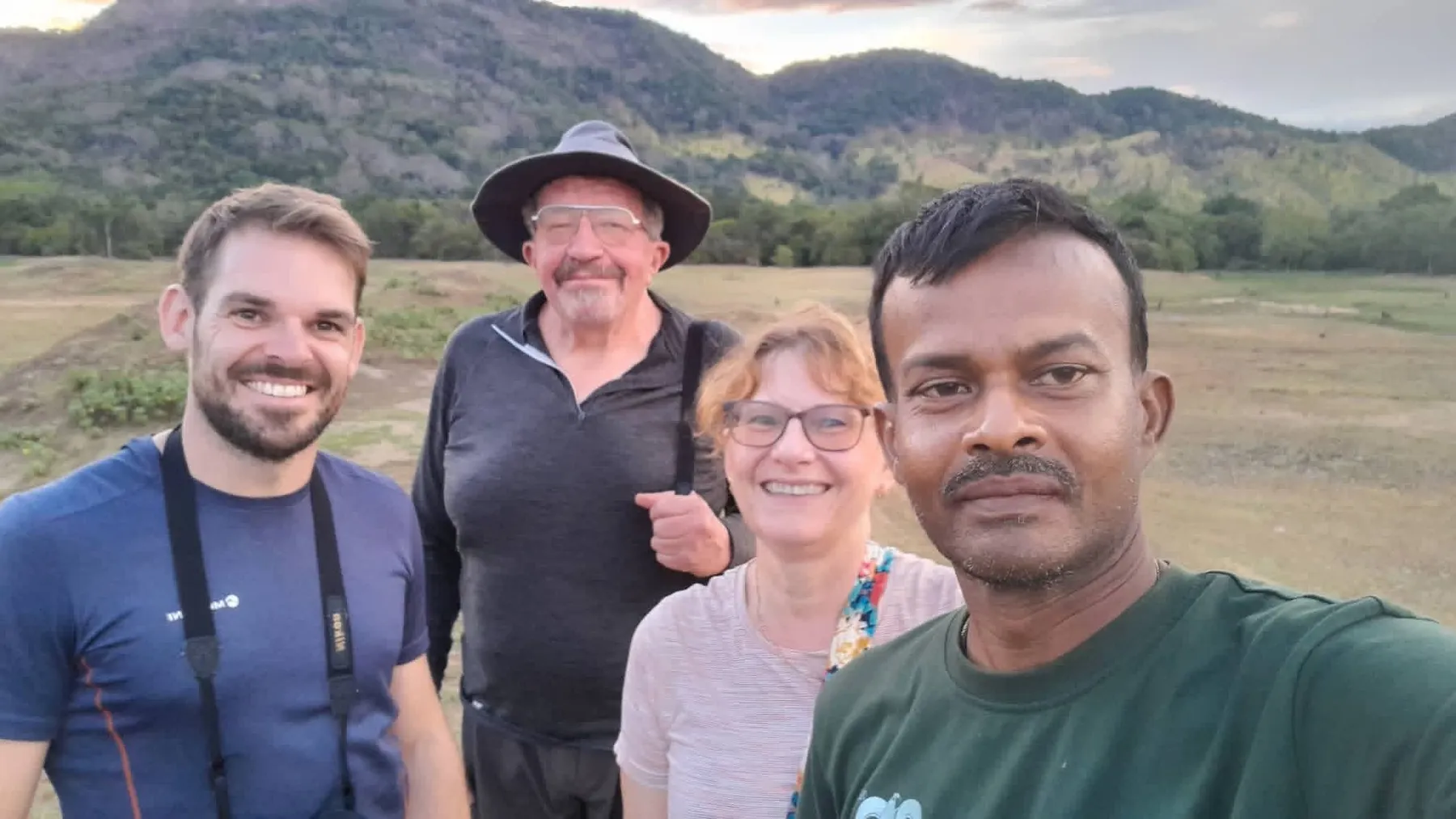 Three volunteers and an SLWCS field guide smiling on the grasslands below the Wasgamuwa hills