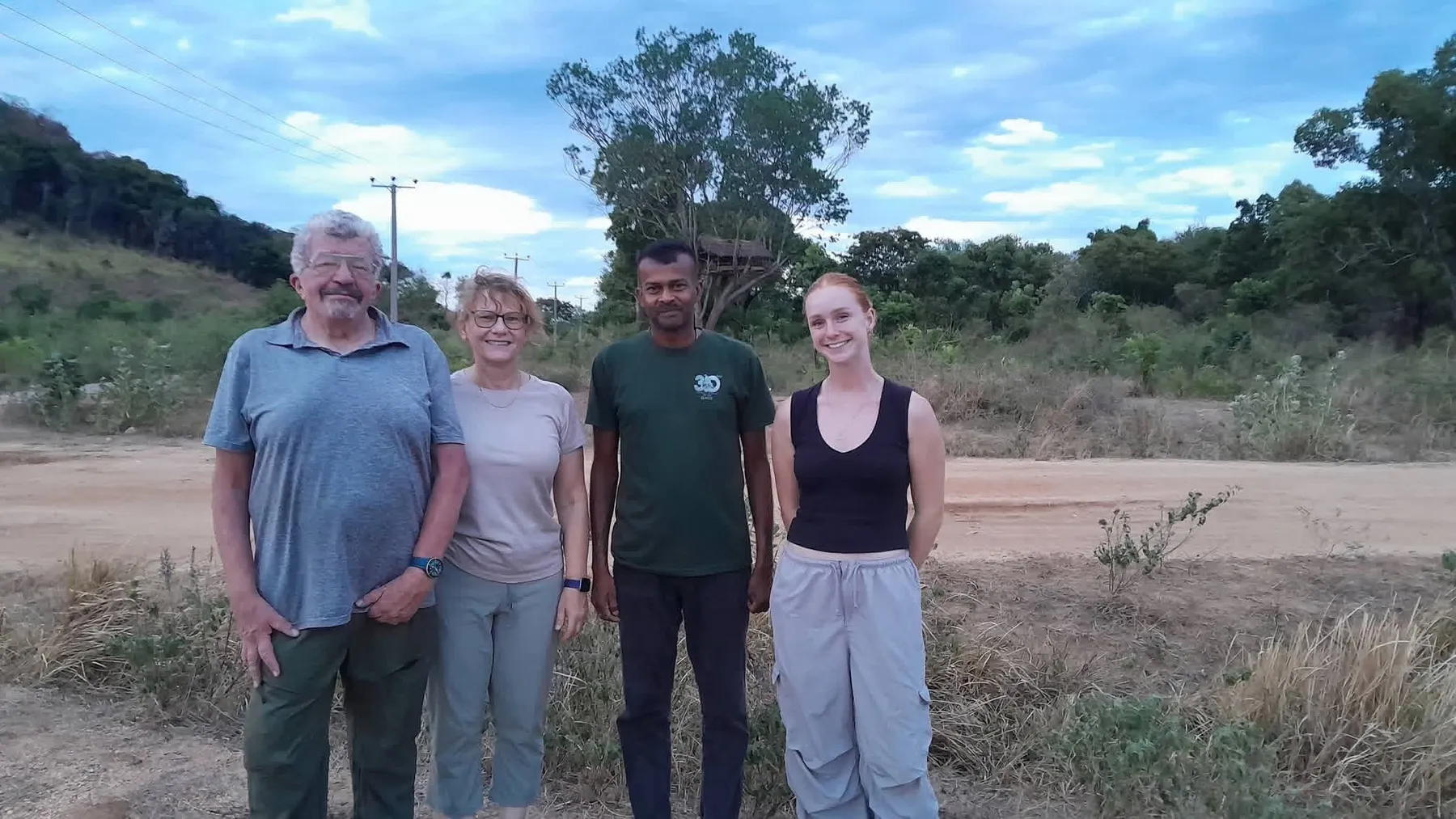 Volunteers standing with an SLWCS field guide on a village road at dusk